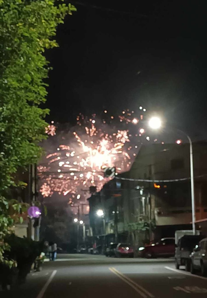 Fireworks explode above a house down the street.